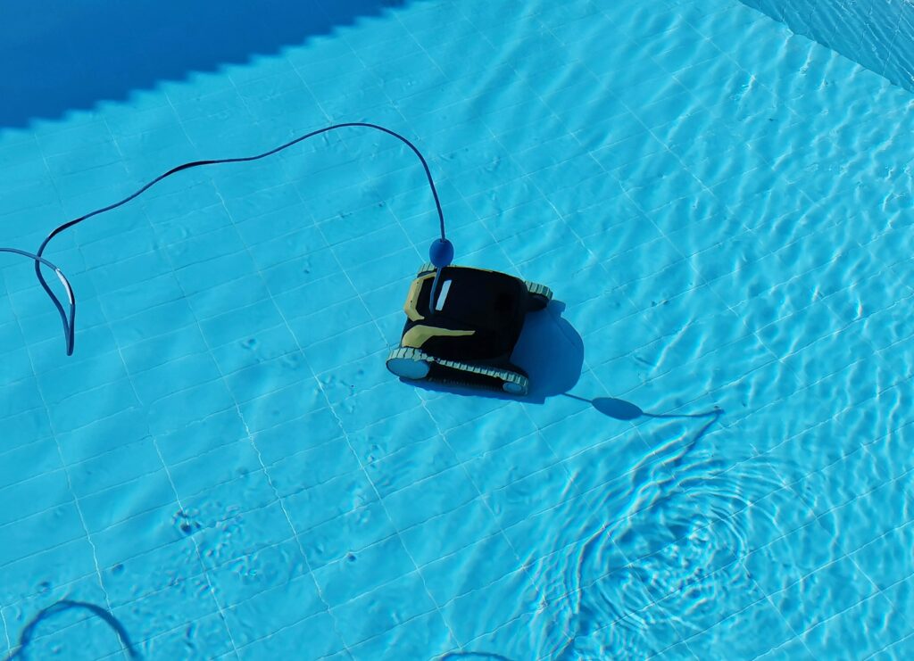 Robot nettoyeur de piscine en action au fond du bassin avec son câble d'alimentation