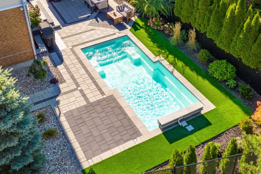Tendances de piscine en 2026 : piscine creusée aux formes géométriques modernes, vue aérienne sur aménagement paysager