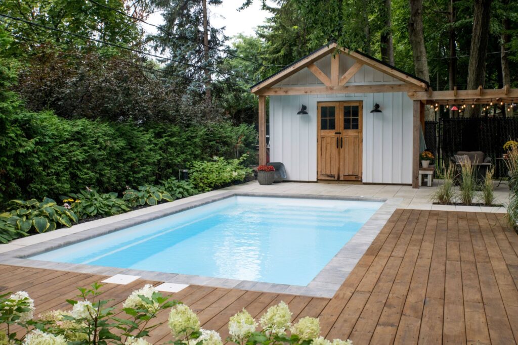 Tendances de piscine en 2026 : piscine intégrée à l'espace avec terrasse en bois et cabanon de jardin