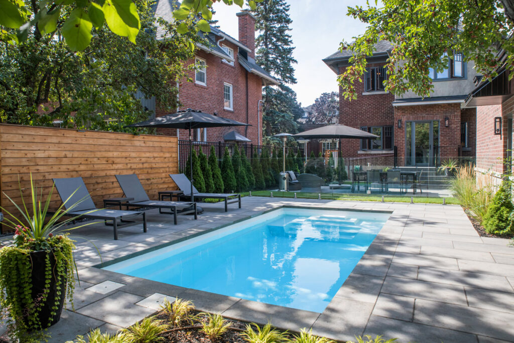 Tendances de piscine en 2026 : petite piscine creusée dans une cour urbaine bordée de chaises longues