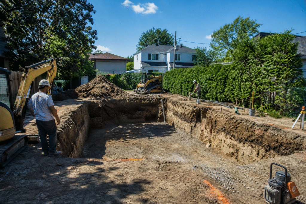 Permis pour piscine creusée : chantier d'excavation avec ouvriers et machinerie dans une cour arrière résidentielle